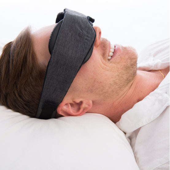 man with head on pillow wearing a blackout sleep mask