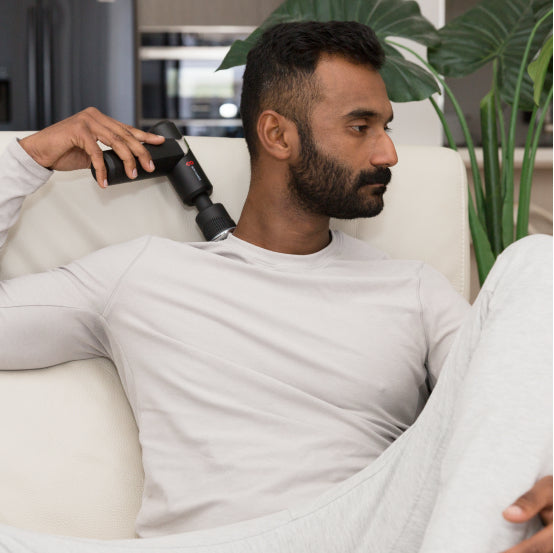 man using massage gun on the side of neck